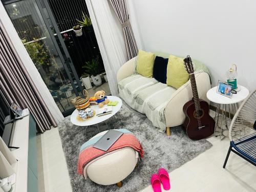 a living room with a couch and a guitar at Livahome - BEE Lux homestay Di An HCMC in Dĩ An