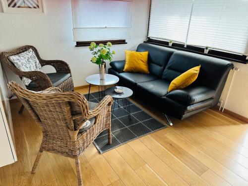 a living room with a black leather couch and chairs at Haus Andrea in Himmelpfort