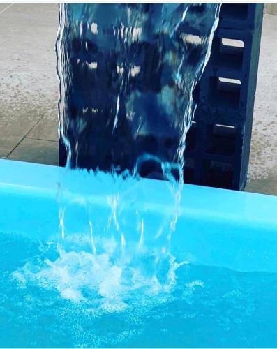 a water fountain in a pool of blue water at Suítes Jasmim in Prado