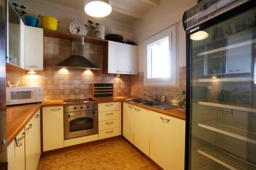 a kitchen with white cabinets and a stove top oven at On the Rocks Villa at Cavo Delos in Agios Ioannis Mykonos