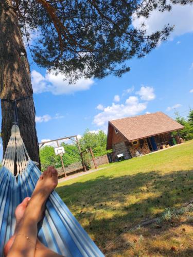 a woman laying in a hammock in front of a house at Podlaska Pieredyszka, dom na wyłączność in Narew