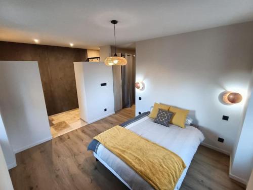 une chambre avec un grand lit avec une couverture jaune dans l'établissement Charmante maison de village, à Le Breuil