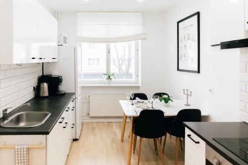 a kitchen with white cabinets and a table and chairs at Gonsiori Apartment in Tallinn