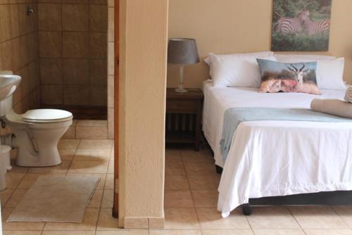 a bedroom with a bed and a bathroom with a toilet at Kruger Bush Retreat in Marloth Park