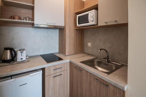 a small kitchen with a sink and a microwave at Hotel Samara with Relax area in Balchik