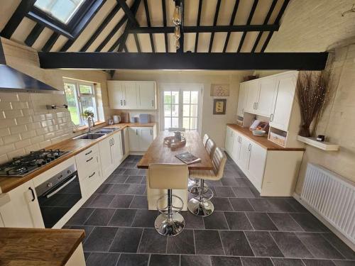 a kitchen with white cabinets and a wooden table at English Farmhouse Cottage in Guildford