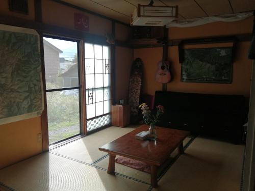 ein Wohnzimmer mit einem Couchtisch und einer Gitarre in der Unterkunft Yukiumi House in Kamikawa