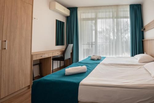 a bedroom with a bed with a desk and a window at Hotel Samara with Relax area in Balchik