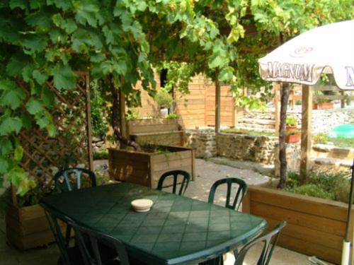 une table verte avec des chaises et un parasol dans l'établissement GITE AVEC PISCINE, à Bessèges