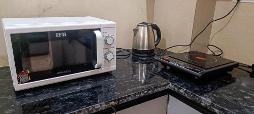 a microwave sitting on top of a counter next to a blender at Hillview 2BHK Flat in Dehradun in Dehradun