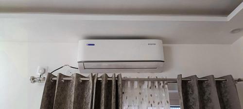 a air conditioner on a wall above a curtain at Hillview 2BHK Flat in Dehradun in Dehradun