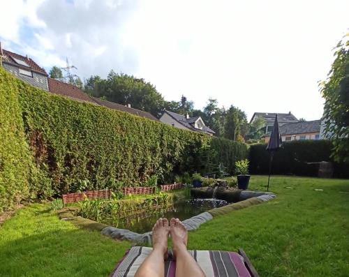 una persona con los pies en un banco en un jardín en Modernes Rhombushaus mit Garten & Teich nähe Wald en Balve