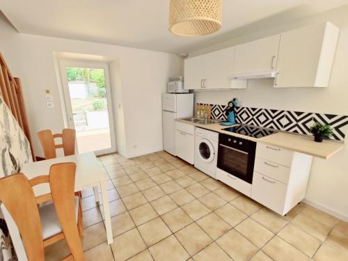 une cuisine avec des armoires blanches et une table dans l'établissement Maison 30m2 - 1 chambre - Jardin, à Fontaine-Étoupefour