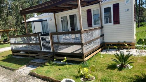 a tiny house with a porch and a deck at bungalow jardim bonito 11zz in Pataias