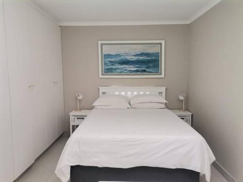 a white bedroom with a large white bed with two night stands at Keurbooms river, San Marino Complex (Unit 53), Self-catering (Plettenberg Bay) in Keurboomstrand
