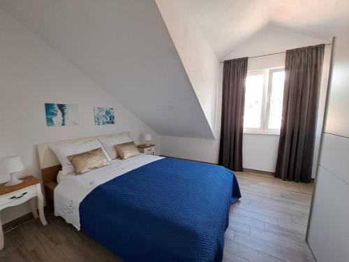 - une chambre avec un lit bleu et une fenêtre dans l'établissement Apartment Teuta, à Žirje