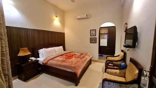 a bedroom with a bed and a tv and a chair at Shelton Hotel & Restaurant in Sarai