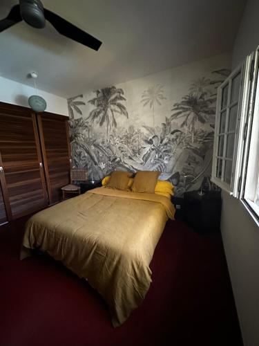 Schlafzimmer mit einem Bett und einem Wandbild von Palmen in der Unterkunft Villa tropicale avec piscine à 5 mn de la plage in Les Avirons