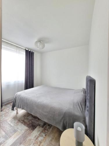 a white bedroom with a bed and a table at Giedres Kalnieciu apartments in Kaunas