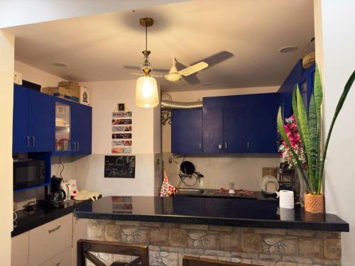 a kitchen with blue cabinets and a ceiling fan at Casa Paradis- secure, cozy& peaceful paradise in heart of most happening colony in Jaipur