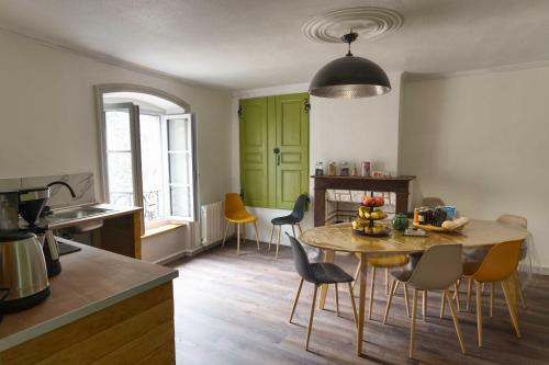 una cocina con armarios verdes, mesa y sillas en Le Repose Pieds, en Le Monastier sur Gazeille