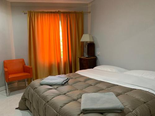 Rodigoにあるbristol palaceのベッドルーム1室(大型ベッド1台、オレンジ色のカーテン付)