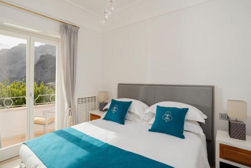 a bedroom with a bed with blue and white pillows at Roberhouse Tragara 37 in Capri