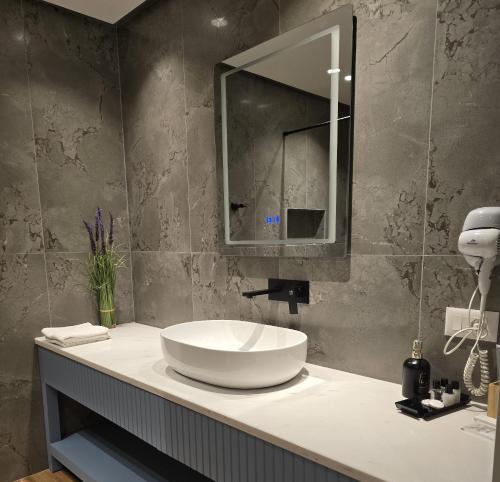 uma casa de banho com um lavatório branco e um espelho. em Perla Hotel em Pogradec
