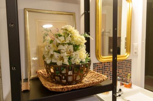a bouquet of flowers in a basket on a bathroom sink at Ruhiges Studio in der Villa Musica mit privatem Sitzplatz & Gemeinschaftspool in Lenzburg