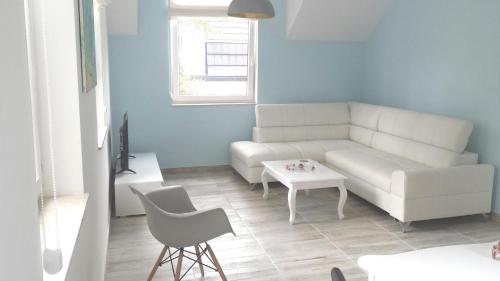 a living room with a white couch and a table at Geräumige Ferienwohnung in Łukcin mit Grill und Terrasse in Łukęcin
