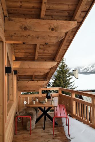 une terrasse en bois avec une table et deux chaises dans l'établissement Chalet Fabriel, à Montgenèvre