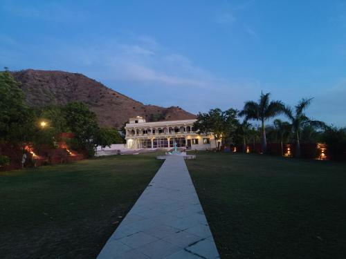duży biały dom z trawnikiem przed nim w obiekcie Monkey Retreat Resort w mieście Udaipur