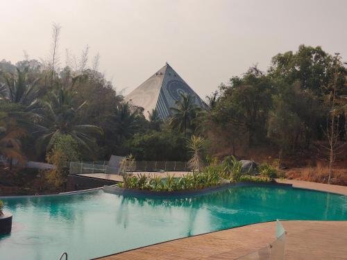 Soul Nest-Pyramid Valley International Bengaluru في بانغالور: مسبح امام مبنى به هرم