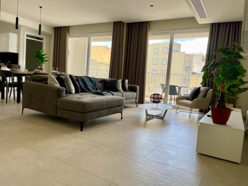 a living room with a couch and a dining room at Bugibba Square Seafront LUX Apartments by Holi in St Paul's Bay