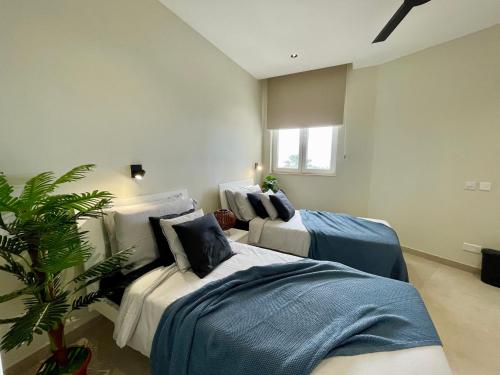 a bedroom with two beds and a potted plant at Bugibba Square Seafront LUX Apartments by Holi in St Paul's Bay
