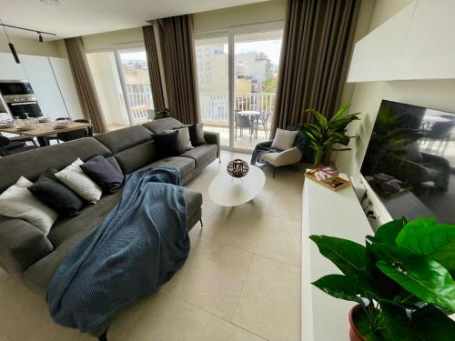 a living room with a couch and a table at Bugibba Square Seafront LUX Apartments by Holi in St Paul's Bay