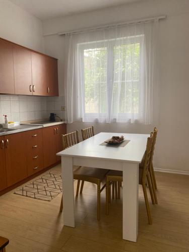 una cocina con una mesa y sillas blancas y una ventana en Vila M Vera Rooms with kitchen and Apartments en Durrës
