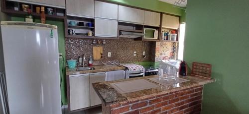 una cucina con pareti verdi e frigorifero bianco di Apartamento Jasmim a Manaus