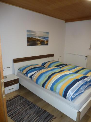 a bedroom with a bed with a colorful striped comforter at Ferienwohnung Rackl in Furth im Wald