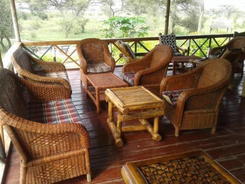 un grupo de sillas de mimbre y una mesa en un porche en Ngalawa Bush Route Hostel, en Dar es Salaam