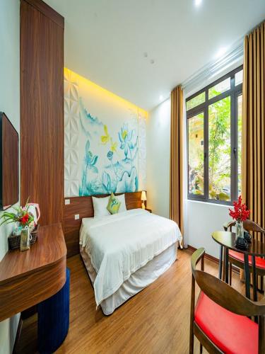 a bedroom with a white bed and a desk and a window at Căn villa Homestay 12 phòng ngủ - bể bơi - Trung tâm Bãi Cháy in Ha Long