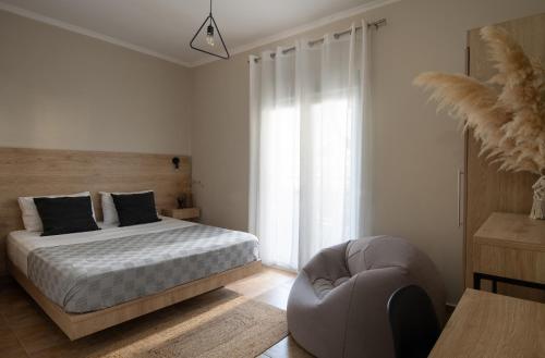 a bedroom with a bed and a chair at StayInn Luxury Apartments in Nea Kalikratia