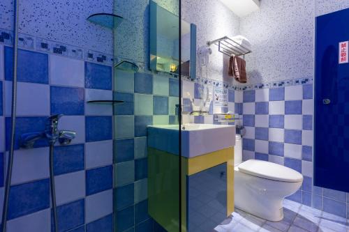 a bathroom with a toilet and a sink and blue and white tiles at Rainbow B&B in Dahan