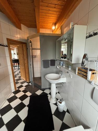 ein Badezimmer mit einem Waschbecken und einem karierten Boden in der Unterkunft Gemütliches Landhaus in ruhiger Lage. in Moringen