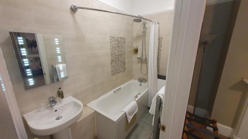 a white bathroom with a sink and a bath tub at Alton House Hotel in Alton