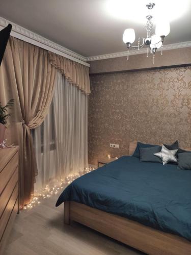 ein Schlafzimmer mit einem blauen Bett und einem Fenster mit Licht in der Unterkunft RentHUB apartment in Chişinău