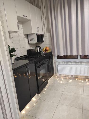 eine Küche mit weißen Schränken und einem schwarzen Herd in der Unterkunft RentHUB apartment in Chişinău