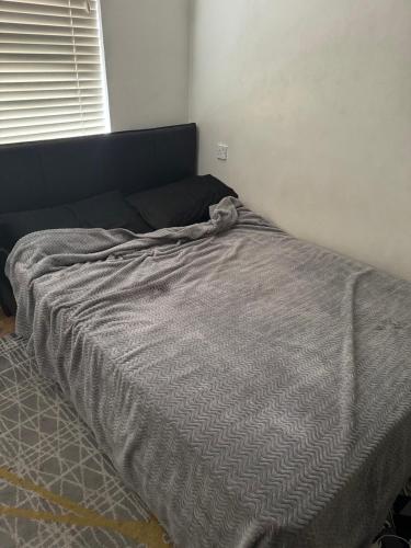 a bed with a gray comforter in a bedroom at 1 bed and breakfast by the Thames in Thamesmead