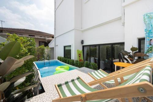 a patio with chairs and a swimming pool at MIQ Ekkamai3_Pool Villa_3BR house in Bangkok