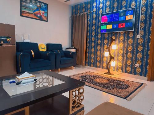 a living room with a blue couch and a tv at SR Apartments Islamabad in Islamabad